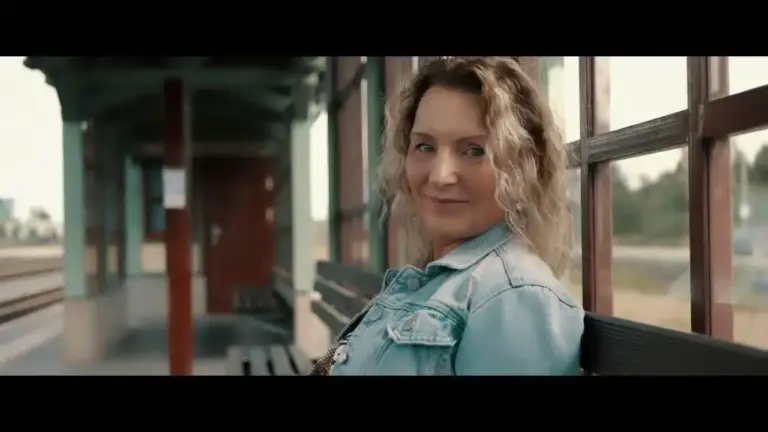 Corinna Anders sitzt in Jeansjacke auf einer Bank am Bahnhof