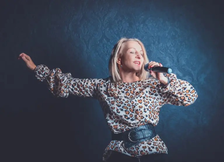 Corinna Anders singt mit geschlossenen Augen ins Mikrofon, in einer Bluse mit Leopardenmuster