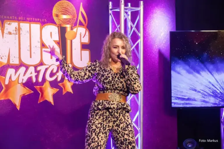 Corinna Anders im Outfit mit Leopardenmuster auf der Bühne von Music Match unter violetten Lichtern