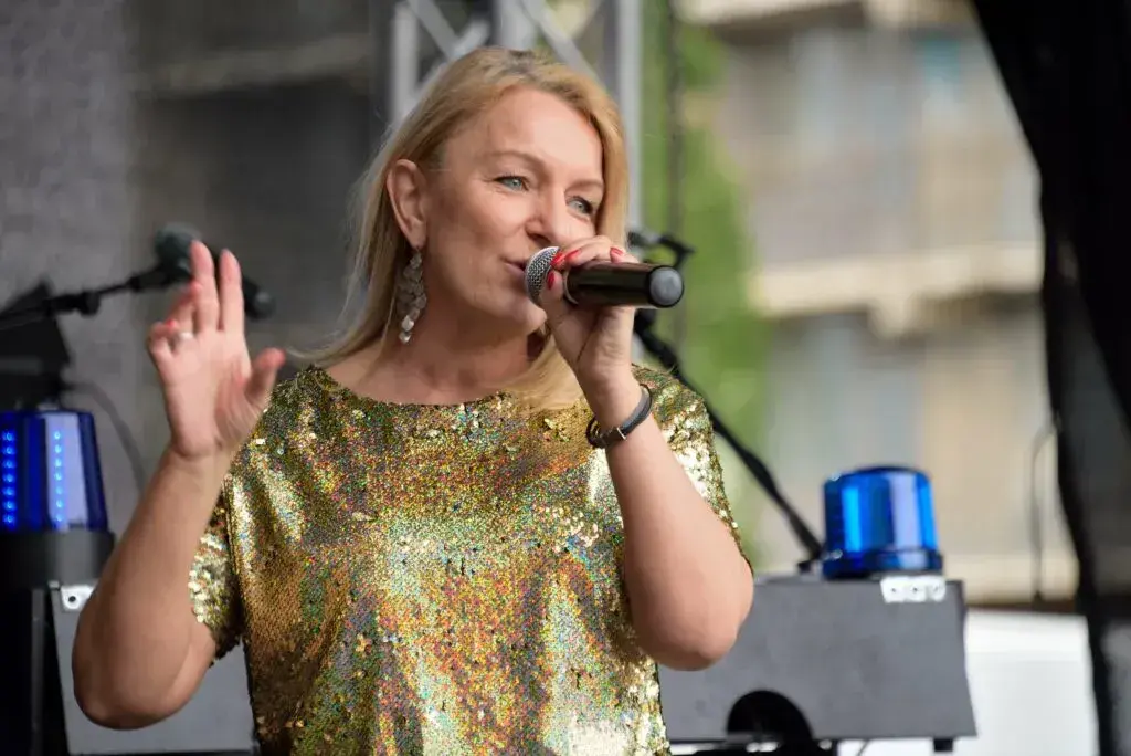 Corinna Anders im goldenen Glitzertop singt bei einer Open-Air-Show ins Mikrofon