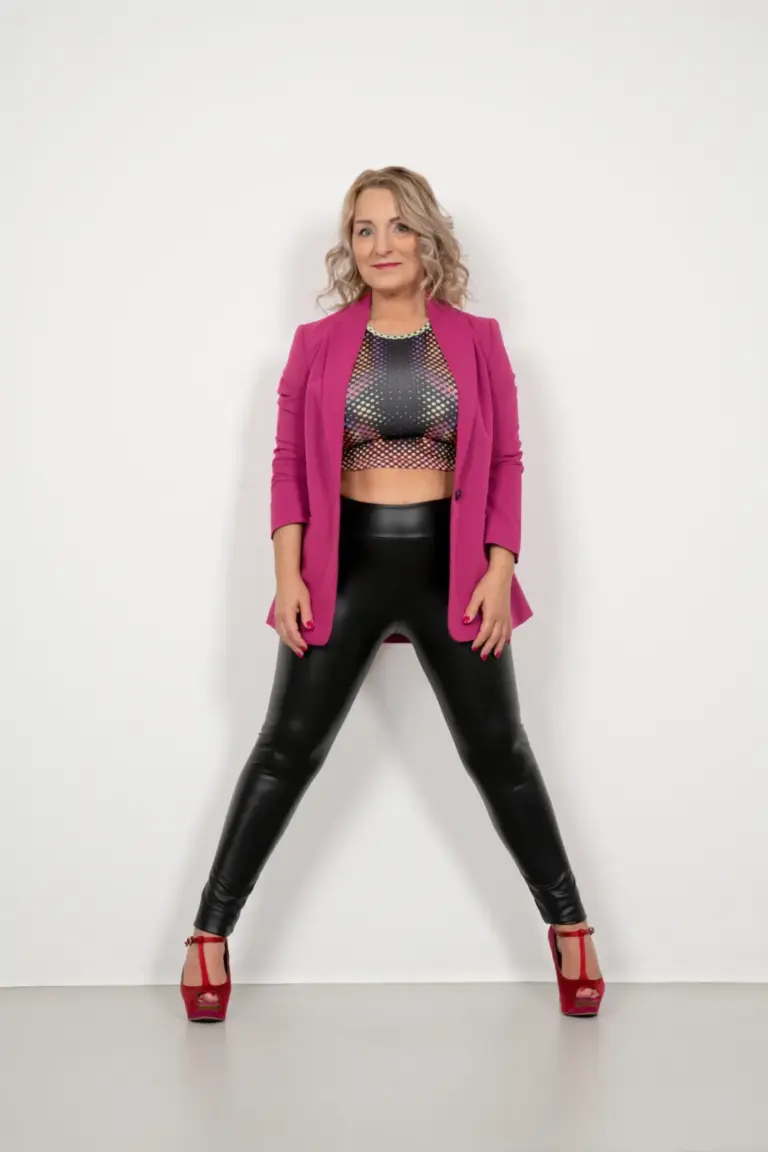 Corinna Anders im rosa Blazer, bauchfreiem Top und roten Heels